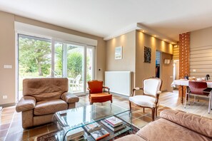 A spacious living area with a glass coffee table, leather sofas, and a dining table with chairs. - Bed and Breakfast 'Une Chambre À Lestriguiou' with Private Terrace, Private Garden and Wi-Fi (Plomeur)