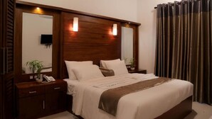 Una camera da letto con una testiera in legno, un comodino con il telefono e un grande specchio.
