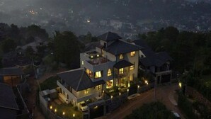 Una casa a più piani con facciata luminosa, immersa nel verde e circondata da altri edifici residenziali.