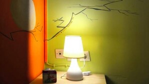 Um quarto com uma luminária, uma parede com pintura de um veado e uma parede com pintura de um galho de árvore.