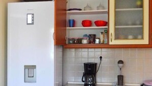 Uma cozinha com geladeira branca, armários de madeira e uma cafeteira sobre a bancada.