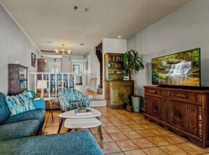 A living room with a sofa, coffee table, TV, bookshelf, and staircase. - Luxury Lakefront Townhome in Rockwall 4 Bedrooms, Minutes from Dallas (Rockwall)