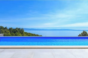 Ein Pool mit Blick auf das Meer und ferne Berge.