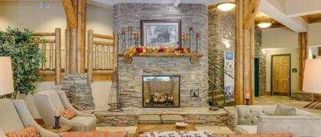 A cozy lobby with a stone fireplace, leather sofas, and wooden beams.
