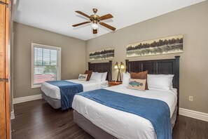A hotel room with two beds, a ceiling fan, a window with blinds, and two paintings on the wall. - Baskins Creek 303 (Gatlinburg)