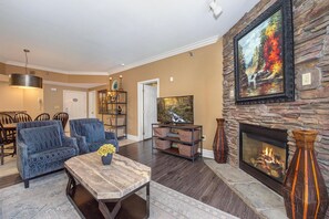 Ein Wohnzimmer mit Kamin, Fernseher und Essbereich mit Stühlen und einem Tisch.