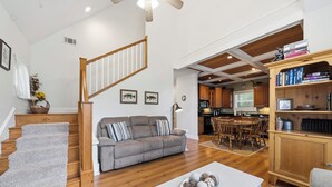 Un salon spacieux avec un canapé gris, une table basse blanche et un escalier menant à une cuisine.