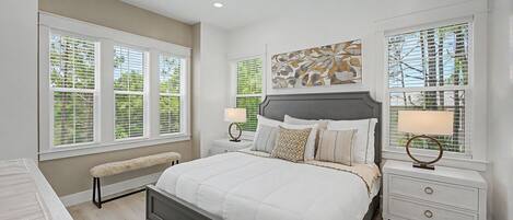 A bedroom with a bed, two bedside tables, a bench, and a ceiling fan.