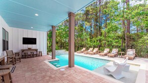 A covered outdoor area with a pool, lounge chairs, and a table with chairs. - Aquarius! New 30A Beach Home with Pool, and Golf Cart. Sleeps 28 (Santa Rosa Beach)