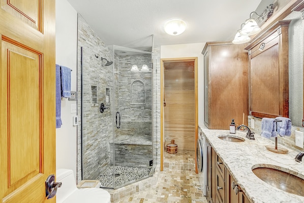 A bathroom with a glass-enclosed shower, a wooden vanity with a sink, and a large mirror.