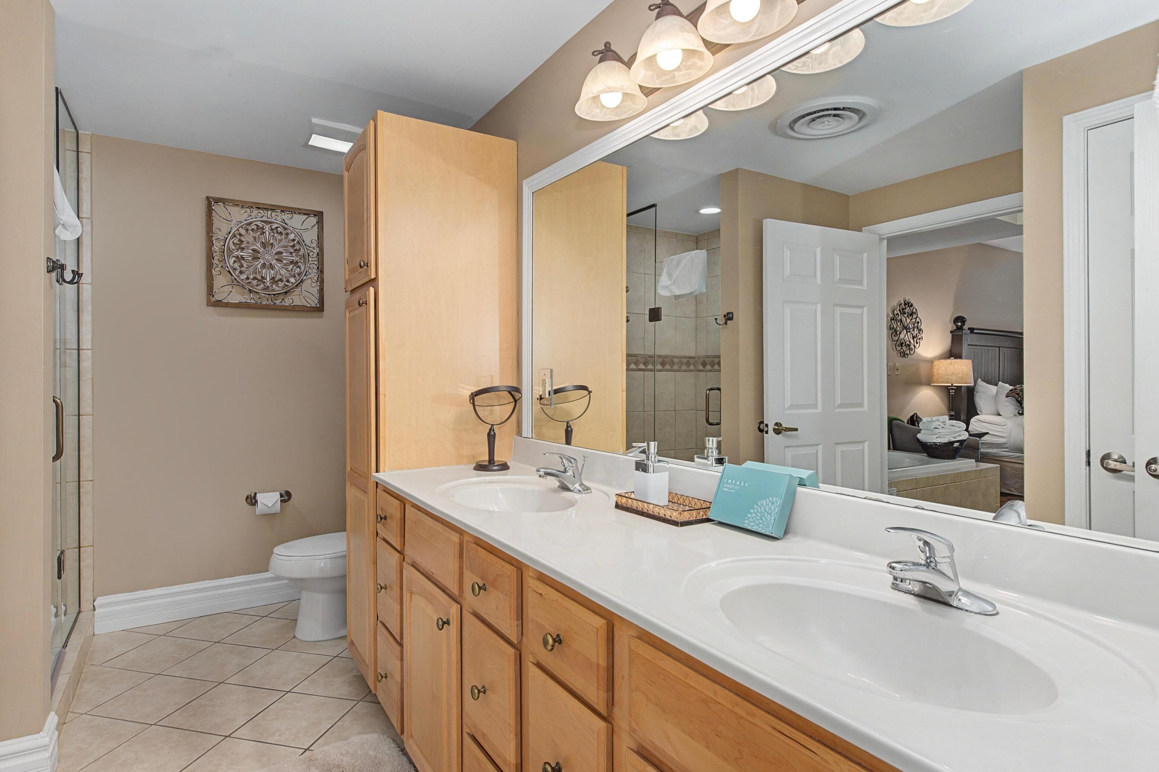 A bathroom with two sinks, a large mirror, and a shower.