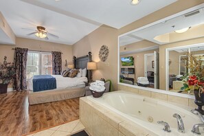 A bedroom with a large bed, a sitting area, a bathtub, and a large mirror. - Baskins Creek 310 (Gatlinburg)