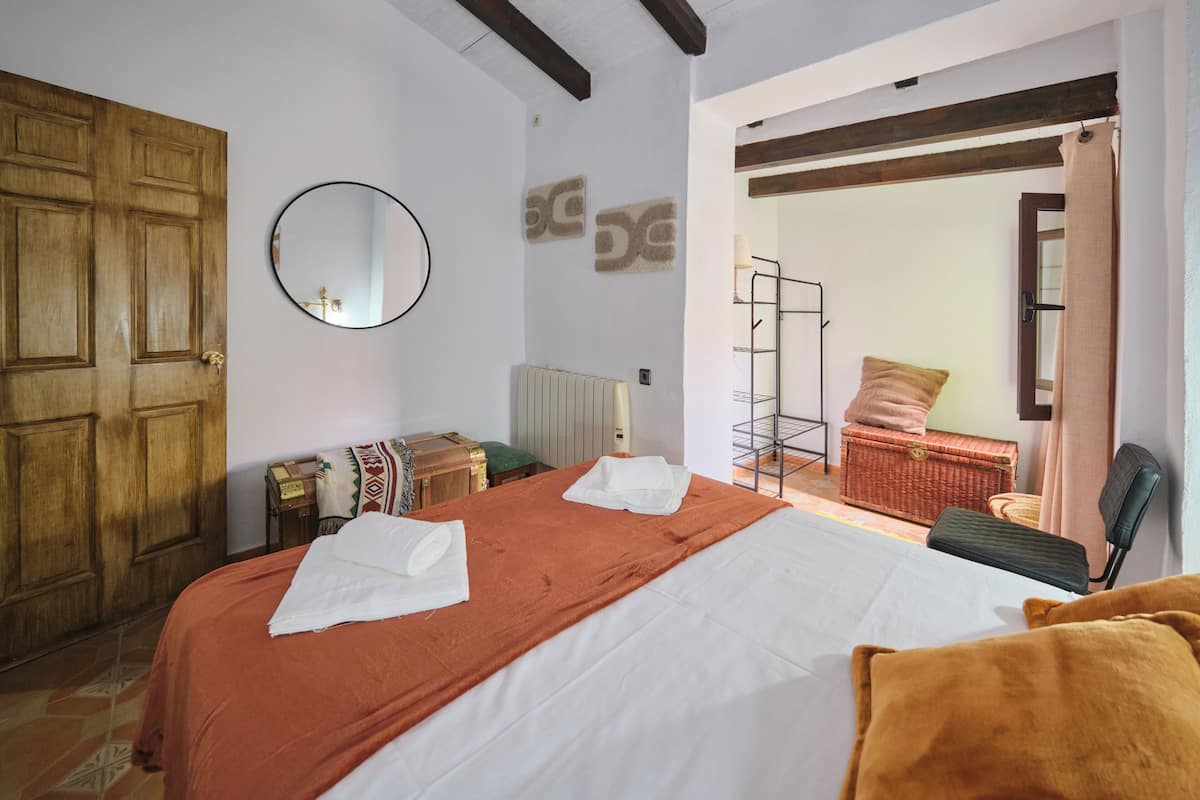 A bedroom with a bed, a wooden door, a mirror, and a radiator.