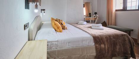 Un dormitorio con cama, mesita de noche y escritorio con silla.