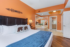Een slaapkamer met een groot bed, een plafondventilator en uitzicht op de badkamer.