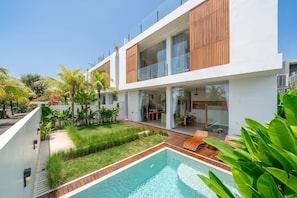 A modern two-story house with a swimming pool, outdoor seating, and lush greenery. - Karma 3 Villa (Badung)