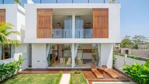 A modern two-story house with a glass balcony, a swimming pool, and a well-maintained lawn. - Karma 3 Villa (Badung)
