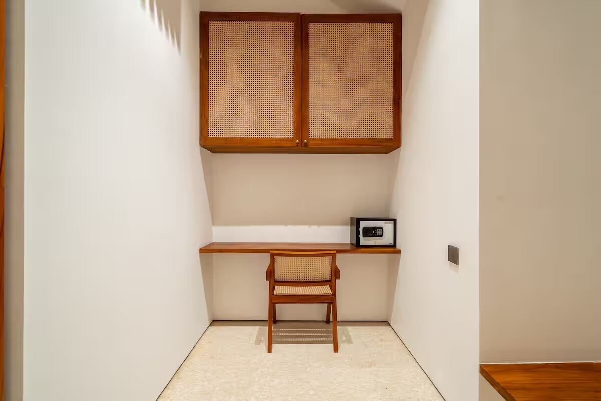 A small room with a wooden desk, a chair, and a wall-mounted cabinet.