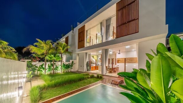 A modern two-story house with a swimming pool, outdoor seating, and lush greenery. - Karma 3 Villa (Badung)