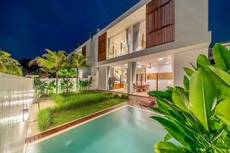 A modern two-story house with a swimming pool, outdoor seating, and lush greenery.. Karma 3 Villa