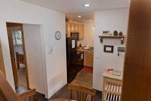 A kitchen with wooden cabinets, a refrigerator, and a clock on the wall. - Sierra Manors Mountain Escape (Mammoth Lakes)