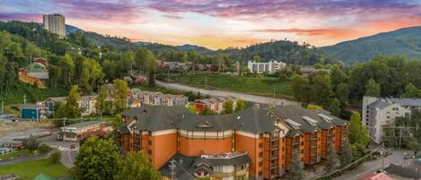 A multi-story hotel with a central courtyard, surrounded by greenery and a hilly landscape.