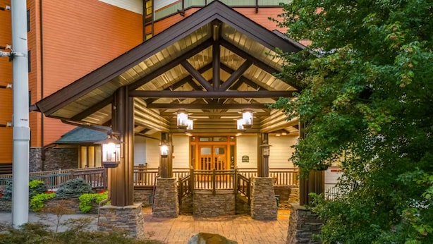 A hotel entrance with a stone facade, wooden porch, and a gated entrance. - Baskins Creek 403 (Gatlinburg)