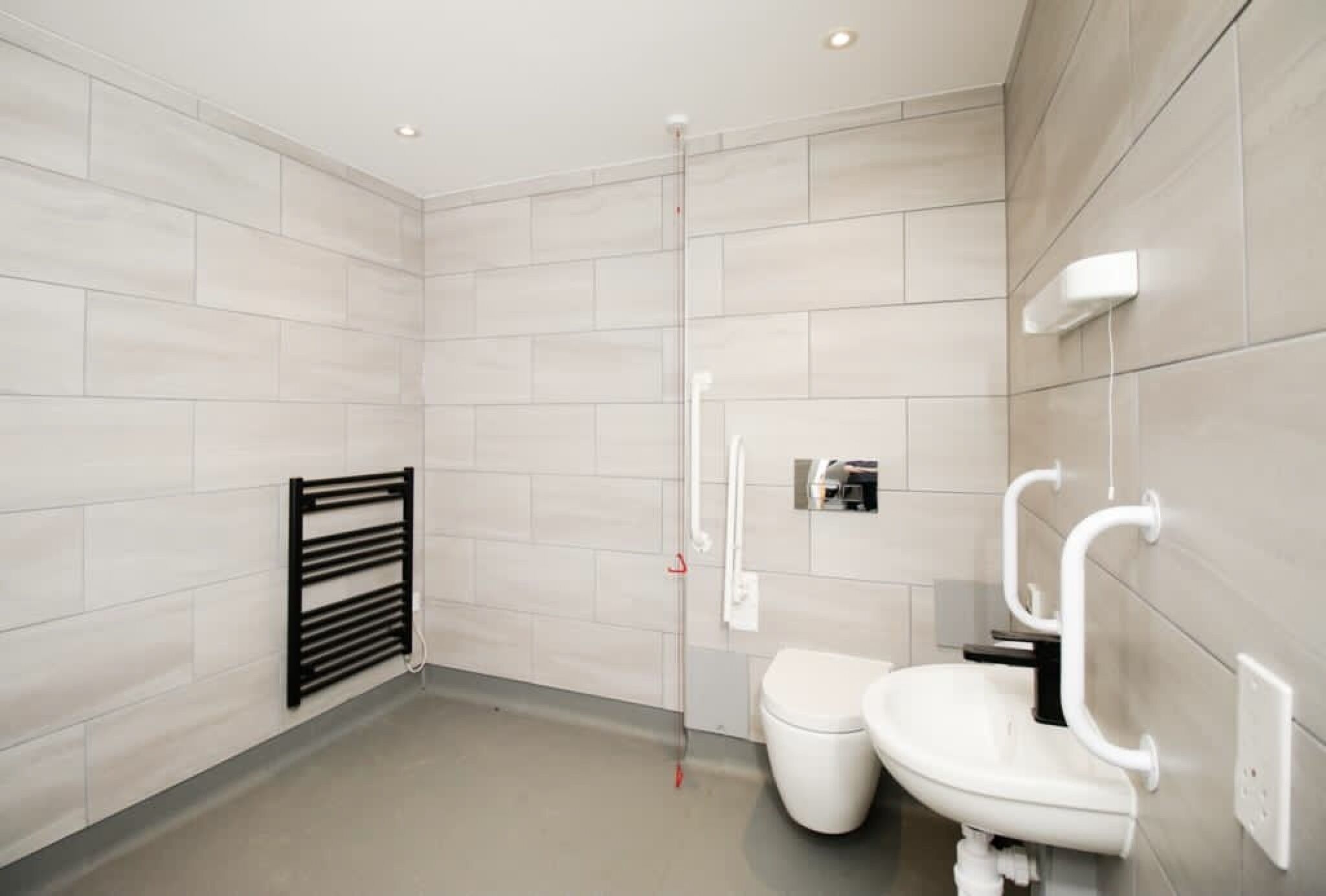 A modern bathroom with a toilet, bidet, and a towel rack.