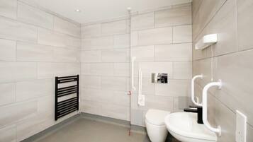 A modern bathroom with a toilet, bidet, and a towel rack.