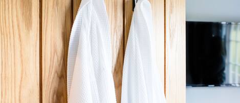 A wooden wardrobe with two white towels hanging on hooks.