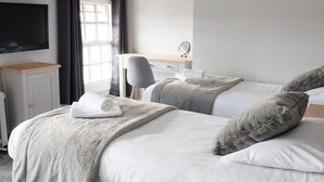 Habitación de hotel con dos camas, un escritorio, un televisor y una ventana con cortinas.