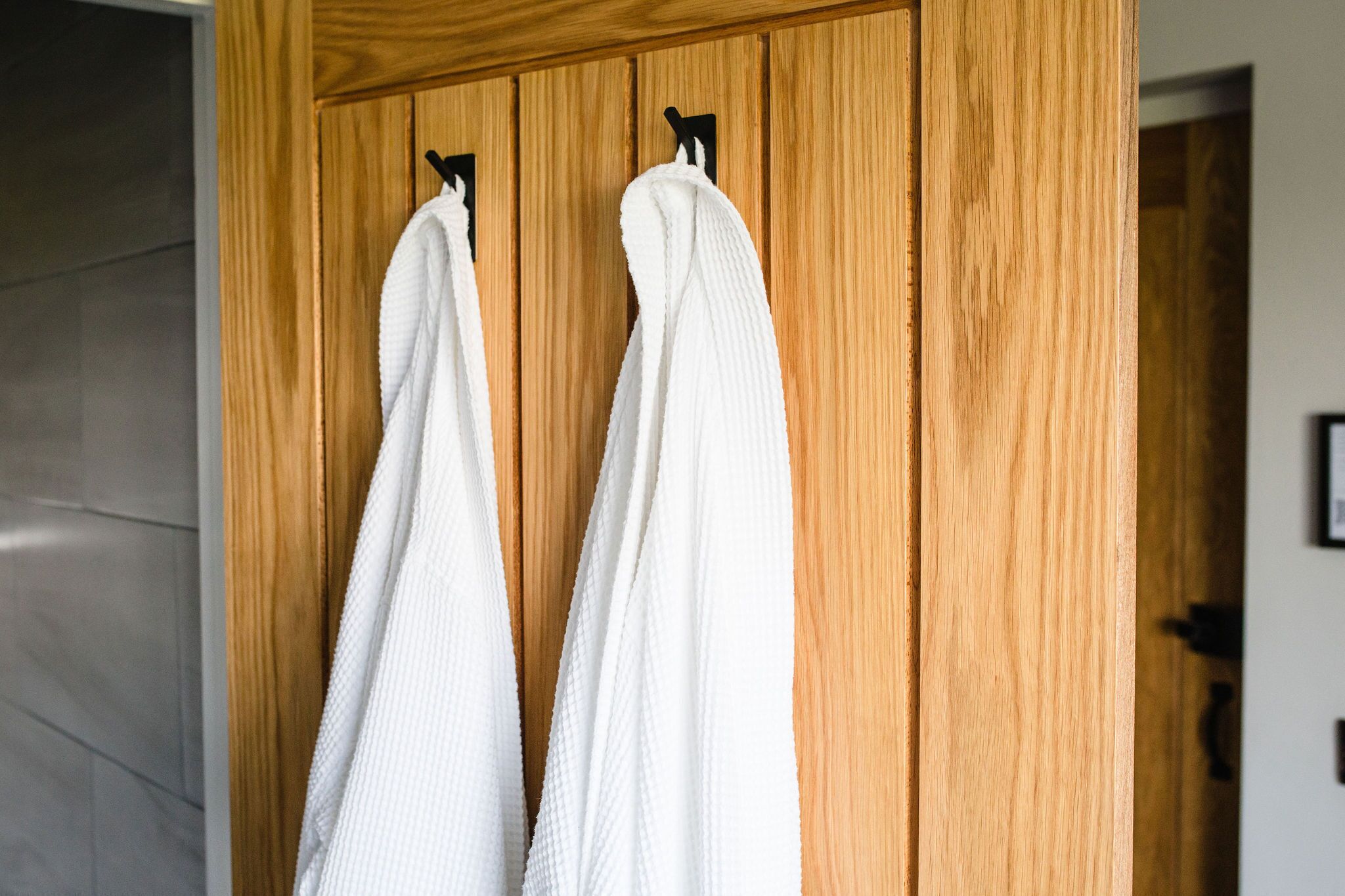 A wooden wardrobe with two white towels hanging on hooks.