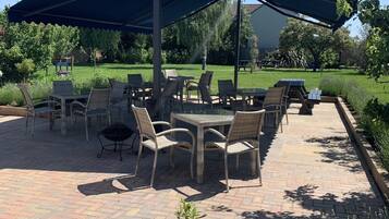 An outdoor patio with wicker furniture, a table, and a large umbrella.