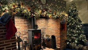 Una habitación acogedora con chimenea de ladrillo, un árbol de Navidad y decoración festiva.