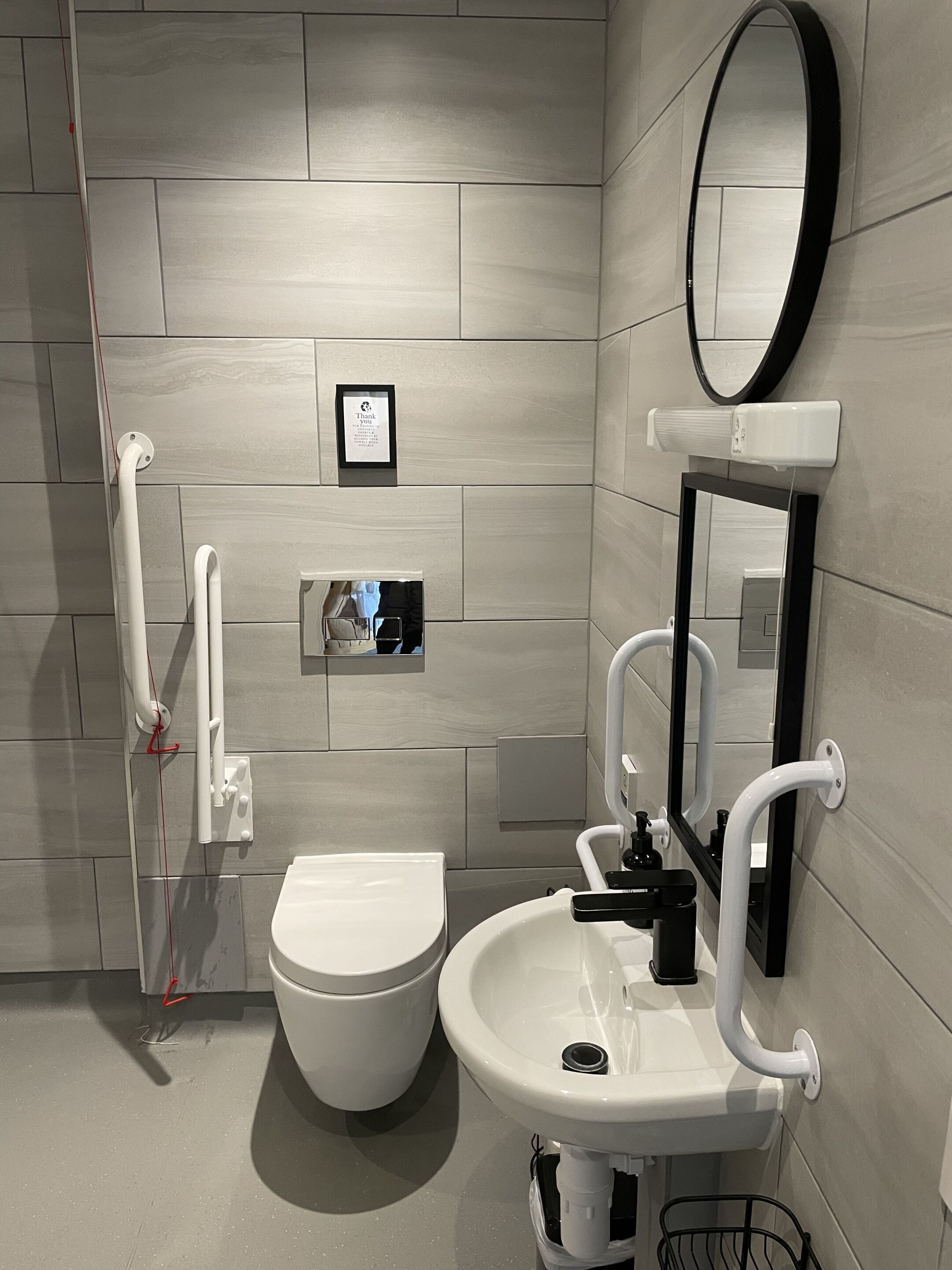 Ein modernes Badezimmer mit Toilette, Waschbecken und Spiegel.