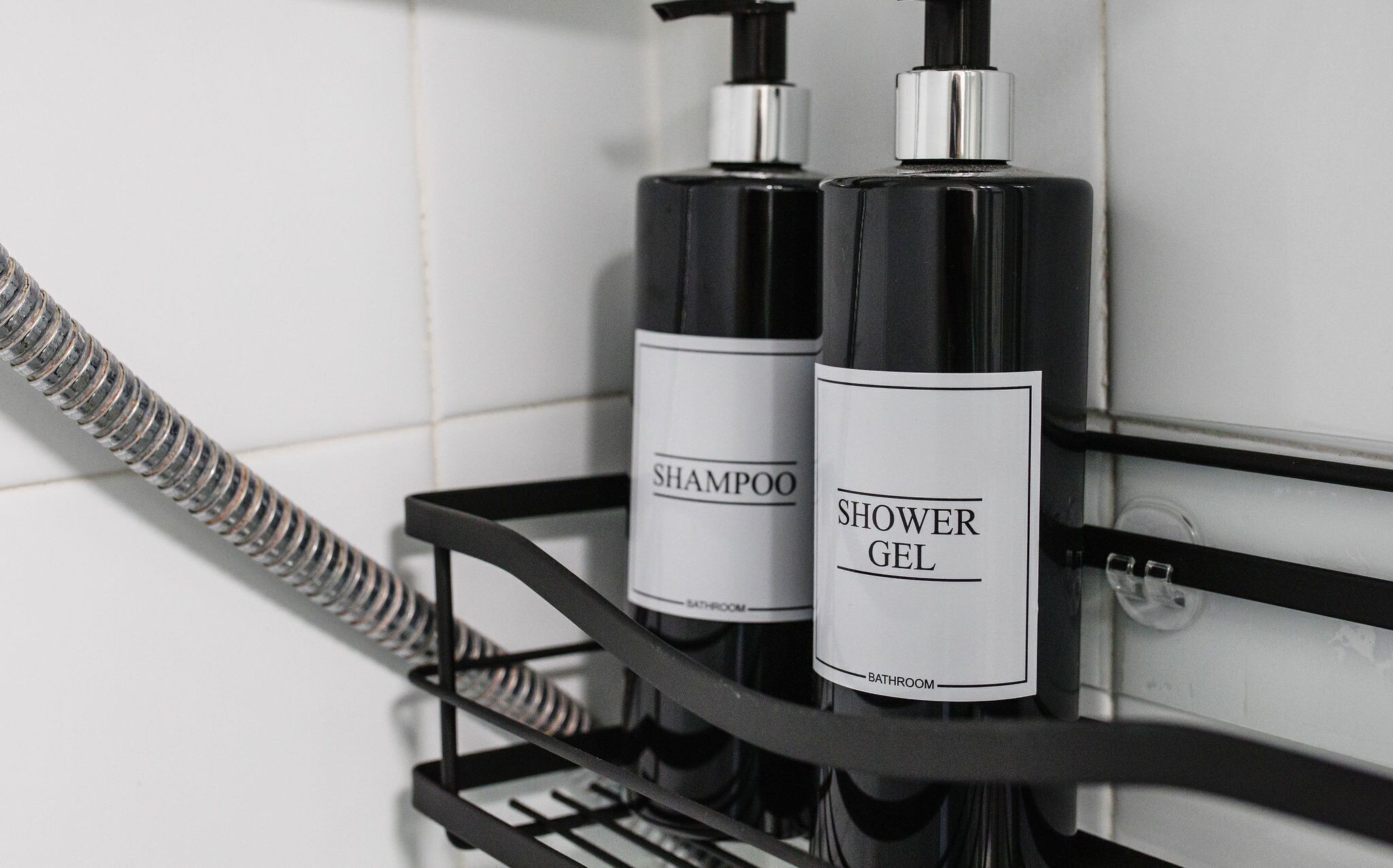 A bathroom shelf with two bottles of shampoo and shower gel.