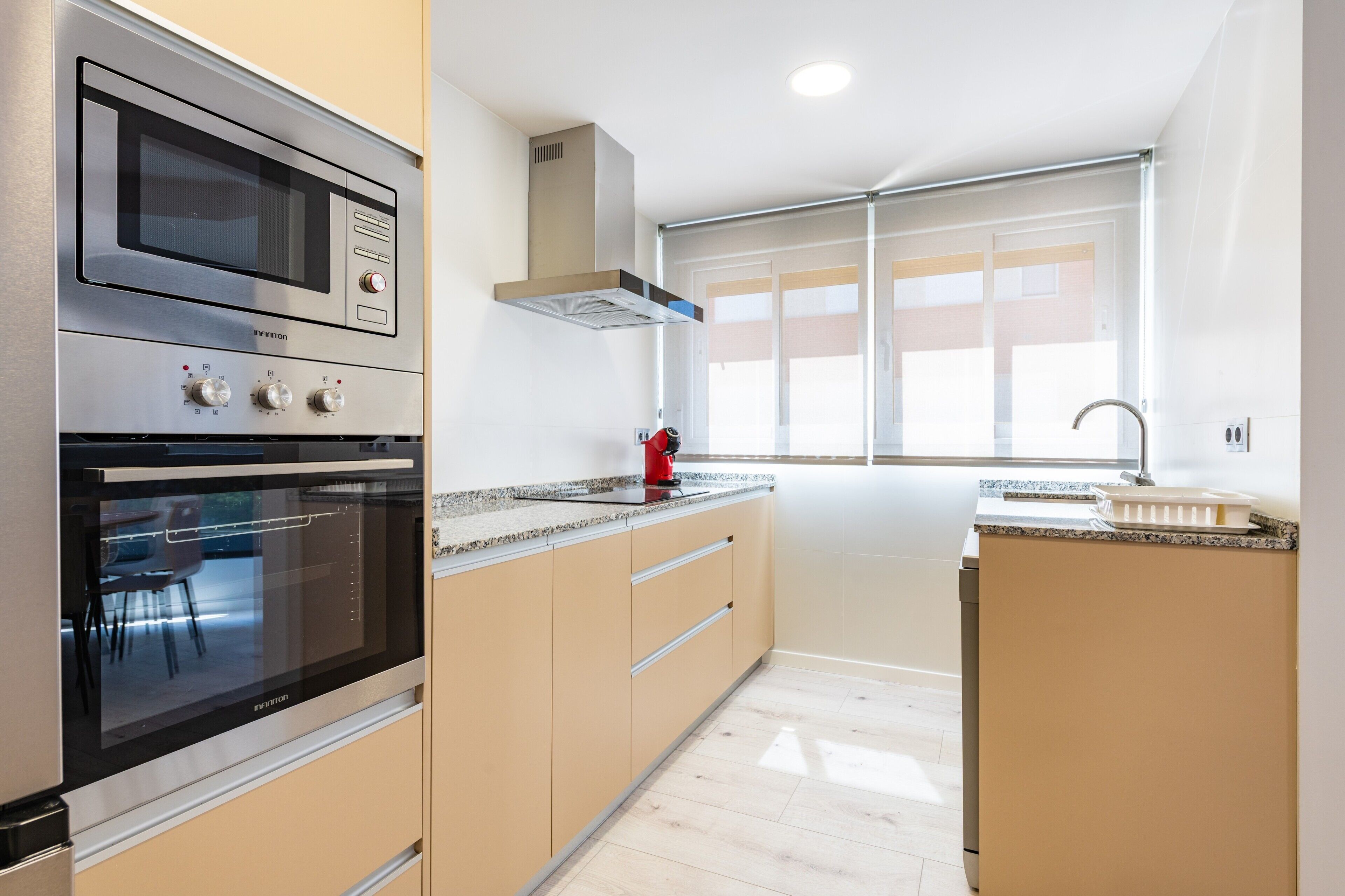 A modern kitchen with a built-in oven, microwave, and a window with a view.