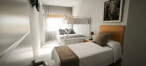 A hotel room with two beds, a window with blinds, a painting on the wall, and a bedside lamp. - Golden Sky Big Families (Benicarló)