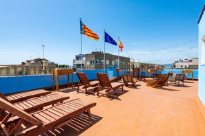 Une terrasse sur le toit, avec des chaises longues, des drapeaux et une vue sur le paysage urbain.
