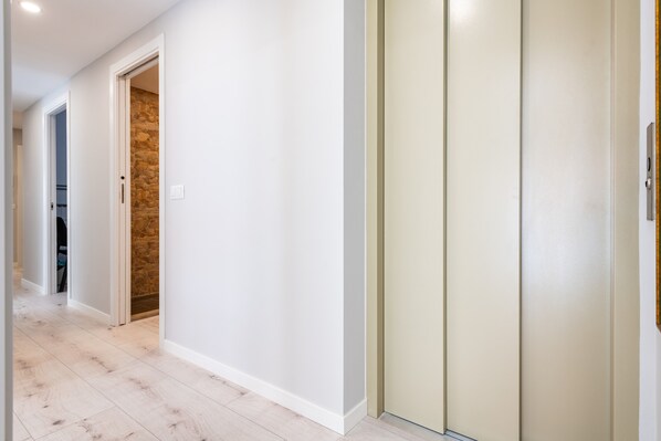 A hallway with a white wall, a stone accent wall, and a beige door.