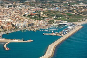 Vista aèria d'una ciutat costanera amb un port esportiu, edificis i una platja.