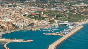 Vista aérea de una ciudad costera con un puerto deportivo, edificios y una playa.