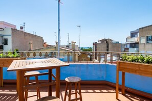 Una terrassa al terrat amb piscina, mobles de fusta i vista a la ciutat.
