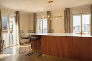 Una cocina moderna con una isla grande, taburetes de bar y una araña.