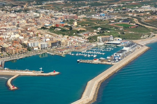 Vue aérienne d’une ville côtière avec un port de plaisance, des bâtiments et une plage.