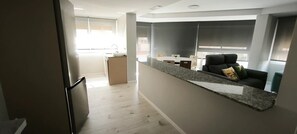 Una cuina moderna amb taulell i zona de menjador amb sofà i cadira.