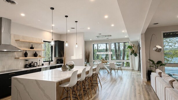 A modern kitchen with a large island, wooden flooring, and pendant lighting. - Modern Deep Creek Lakefront Home, Movie Theater, Hot Tub, 7BR/6BA, Sleeps 16 (Oakland)