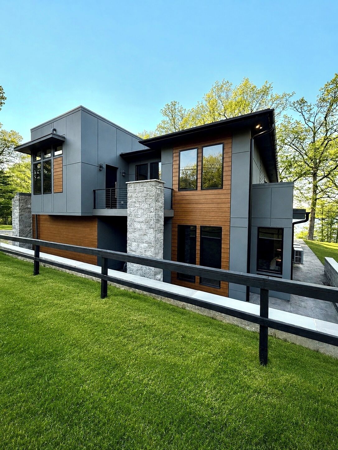 A modern two-story house with a stone pillar, wooden accents, and a balcony.