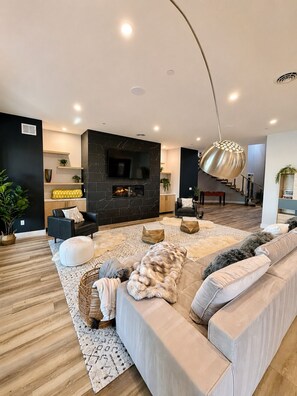 Ein modernes Wohnzimmer mit Kamin, Sofa und einer Treppe, die in eine weitere Ebene führt.