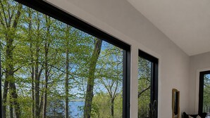 A modern room with large windows, a glass table, and a chair. - Modern Deep Creek Lakefront Home, Movie Theater, Hot Tub, 7BR/6BA, Sleeps 16 (Oakland)